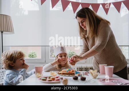 Mutter zündet die Kerzen auf dem Kuchen an Stockfoto