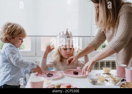 Frau teilt süße Schokolade Dessert mit Flagge auf rosa Teller Mit Kindern zu Hause Stockfoto