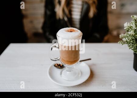 Cropped unkenntlich trendy schöne blonde Frau trinkt aus einem Glas köstlichen Schaum Kaffee Stockfoto