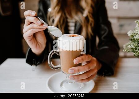Cropped unkenntlich trendy schöne blonde Frau trinkt aus einem Glas köstlichen Schaum Kaffee Stockfoto