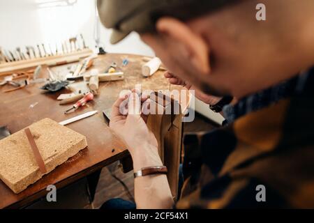 kaukasische Leder Handwerk Schnurrbart Mann trägt Tasse arbeiten als Handwerker In seiner Werkstatt Stockfoto