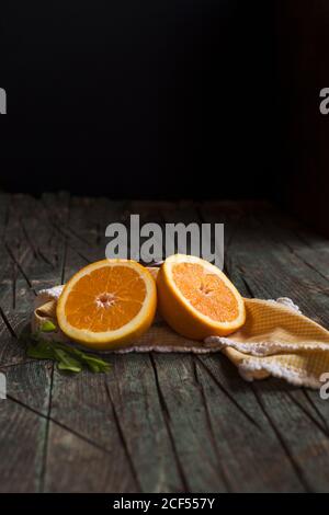 Hälften von frischen Orangen auf einem dunklen rustikalen Holztisch Auf einem dunklen Hintergrund Stockfoto