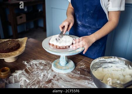 Koch verschönert einen leckeren Kuchen mit Sahne Stockfoto