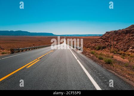 Ländliche Asphaltstraße zwischen den Feldern in der Sommersaison. Stockfoto