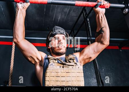 Starker Mann tut Pull-up-Übung mit Gewicht auf horizontalen Stab Stockfoto