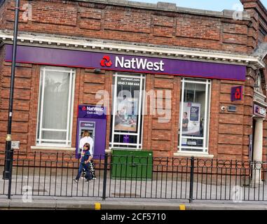 Eine Frau nutzt den Außenautomaten (Automated Teller Machine) bei einer NatWest Bank an der Bury New Road in Prestwich, Manchester, England. Stockfoto