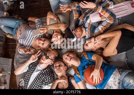 Glückliche Gruppe von Frauen und Männern Gesichter im Kreis lachen und Spaß Draufsicht, auf Decke liegen, freudige Momente Feier Stockfoto