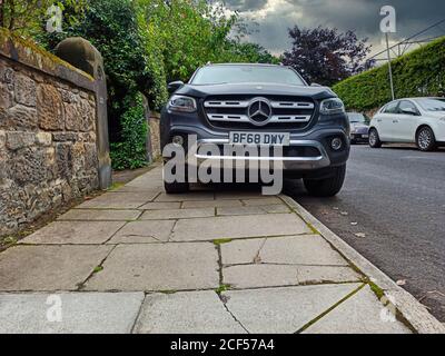 Ein Parkplatz auf dem Bürgersteig / Bürgersteig, Beschränkung Platz für Fußgänger und zeigt Schäden an Pflasterflaggen - in Großbritannien genommen Stockfoto