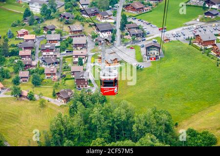 Grindelwald - Blick auf die rote Pfingstegg-Seilbahn und Talstation, hinauf über das Dorf Grindelwald, Berner Oberland, Schweiz Stockfoto