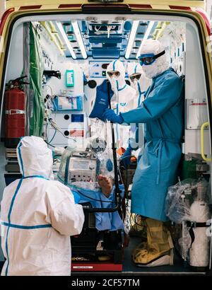 Gruppe von professionellen Ärzten in Schutzuniform im Krankenwagen stehen Auto mit Ausrüstung und Vorbereitung für den Patiententransport Stockfoto