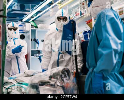 Gruppe von professionellen Ärzten in Schutzuniform im Krankenwagen stehen Auto mit Ausrüstung und Vorbereitung für den Patiententransport Stockfoto