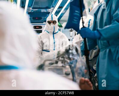 Gruppe von professionellen Ärzten in Schutzuniform im Krankenwagen stehen Auto mit Ausrüstung und Vorbereitung für den Patiententransport Stockfoto