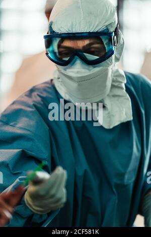 Professionelle Chirurg in Schutzuniform mit Handschuhen und Maske Durchführung Operation im Operationssaal im modernen Krankenhaus Stockfoto