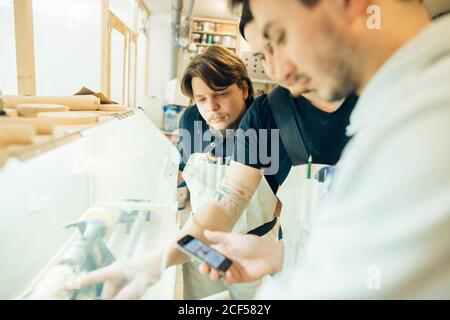 Zimmermann schreibt jemanden auf seinem Smartphone in einer staubigen Werkstatt. Stockfoto