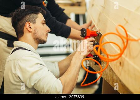 Carpenter brad mit Nagelpistole, um Tür Rahmung trimmen, mit dem Warnschild, dass alle Elektrowerkzeuge haben auf ihnen gezeigt, die Sicherheit concep veranschaulichen Stockfoto