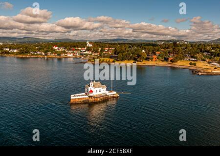 Der ehemalige Dyna-Leuchtturm im Oslofjord in der Nähe von Oslo, Norwegen, wurde 1875 erbaut und 1992 zu einem Restaurant mit Platz für 20 bis 40 Gäste umgebaut. Das kleine felsige Inselchen mit dem Restaurant liegt umgeben von Fjordwasser und bewaldeten Ufern. Stockfoto