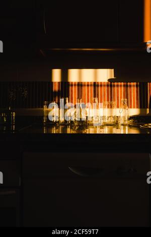 Leere Gläser unter dramatischem Licht auf einer Kochplatte eines Dunkle Küche Stockfoto
