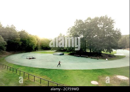 Junge, fit Frau, die an einem sonnigen Tag auf einer Strecke im Freien läuft Stockfoto