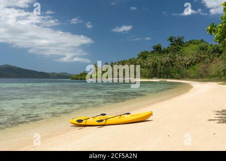 Leeres gelbes Kanu am Sandstrand der tropischen Insel Hintergrund von Dschungel und blauen Himmel Stockfoto