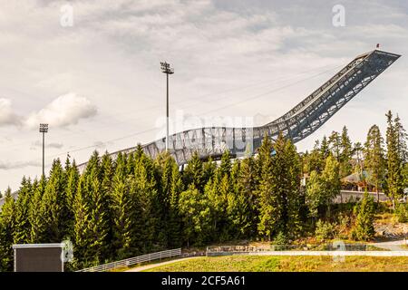 Die Holmenkollen-Skischanze ragt über die Baumwipfel nahe Oslo, Norwegen. Der aktuelle, etwa 60 Meter hohe Turm, der 2010 von den Architekten JDS/Julien De Smedt neu gebaut wurde, war Gastgeber der Olympischen Winterspiele 1952 und mehrerer Nordischer Ski-Weltmeisterschaften. Stockfoto