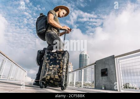 Reisender Mann SMS Telefon mit seinem Gepäck zu Fuß auf Ocean Drive South Beach Florida. Reisekonzept Stockfoto