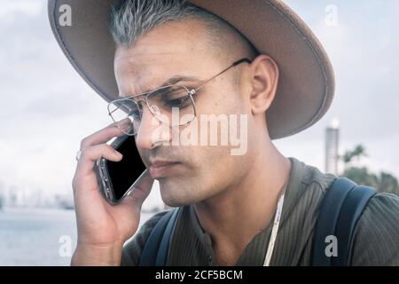 Junger Mann mit Hut und Gespräch am Handy mit besorgten Ausdruck. Hochformat Stockfoto