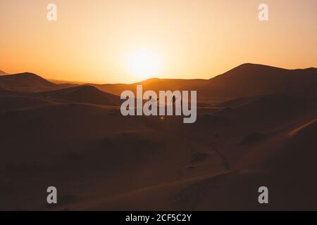 Minimalistischer Blick auf Kamele Silhouetten auf Sanddüne in der Wüste gegen Sonnenuntergang Licht, Marokko Stockfoto