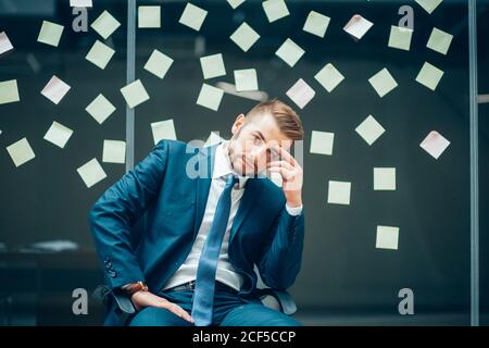 Geschäftsmann in Kopfschmerzen während einer Konferenz - depressive Person mit finanziellen Schwierigkeiten Stockfoto