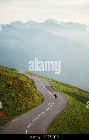 Landschaftlich schöne Aussicht auf die Berge und man Skateboarding auf der Straße Stockfoto