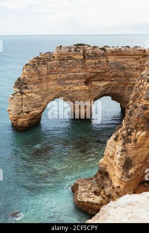 Sauberes Meerwasser plätschert in der Nähe gewölbte raue Klippe auf Ruhe Tag in Portugal Stockfoto