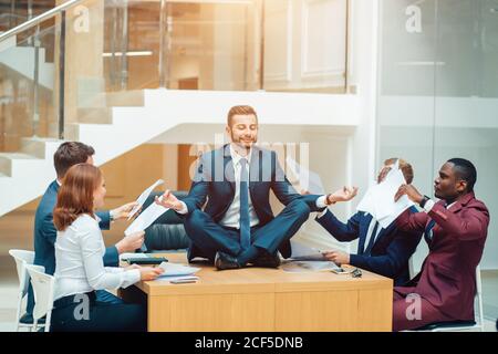 Junge gut aussehende Geschäftsmann in schwarz Anzug Praxis Yoga und Entspannen Sie sich im Büro und stellen Sie das Konzept der Stresskontrolle dar Stockfoto