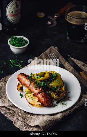 Im Ofen gebackene Schweinewurst mit Paprika, Zwiebeln und verschiedenen Kräutern Stockfoto