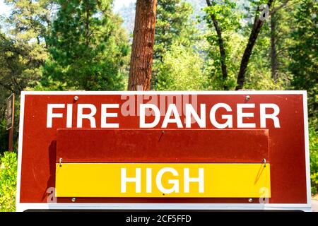 Ein Warnschild mit hoher Brandgefahr informiert die Öffentlichkeit darüber, dass es wahrscheinlich ist, dass es zu Waldbränden kommt. Grüner Wald Hintergrund. Stockfoto