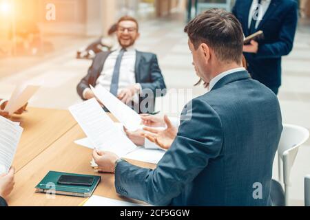 Geschäftsmann hält Papiere Hände und lächelnd.Junges Team von Mitarbeitern machen Tolle Geschäftsdiskussion im modernen Coworking Office Stockfoto