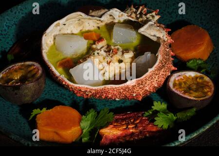 Closeup herzhafte Cheviche in Spinnenkrabben Schale mit Arthropode serviert Fleisch und verschiedene tropische Früchte auf dem Teller Stockfoto
