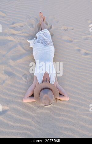 Von oben Frau in weißem Kleid und Hut am Sandstrand in Tarifa, Spanien Stockfoto