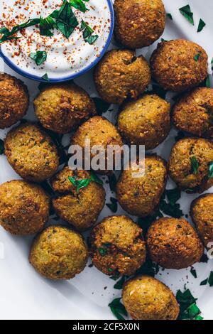 Draufsicht auf frittierte Falafel aus Hülsenfrüchten serviert mit Saure Sahne-Sauce auf dem Teller Stockfoto