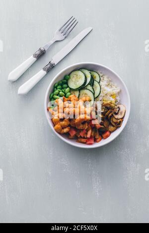 Draufsicht auf weiße Poke Schüssel mit Reis und Gurke Mit Bohnen und Pilzen mit Garnelen Stockfoto