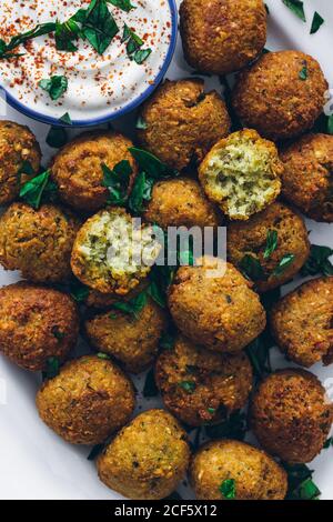 Draufsicht auf frittierte Falafel aus Hülsenfrüchten serviert mit Saure Sahne-Sauce auf dem Teller Stockfoto