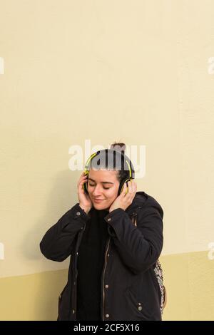 Zufriedene junge Dame lächelnd, während Musik in den Kopfhörern hören Stockfoto