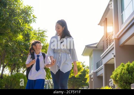 Glückliche asiatische Mutter und Tochter Grundschüler zu Fuß zur Schule am Morgen Schulroutine für den Tag im Leben immer bereit für die Schule. Stockfoto