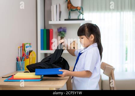 Asiatische nette Grundschulmädchen Verpackung ihre Schultaschen, die Vorbereitung für den ersten Tag der Schule. Die morgendliche Schulroutine für den Tag im Leben getti Stockfoto