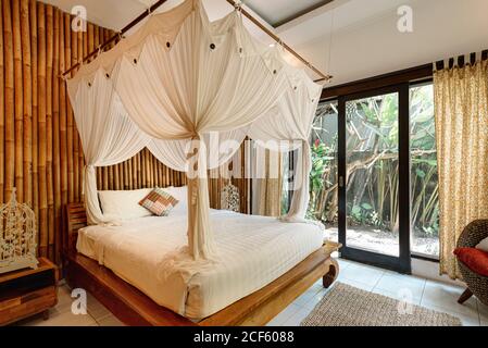 Helle Innenausstattung des Schlafzimmers im Hotel mit Bambuswand und Gemütliches Himmelbett in Bali Stockfoto