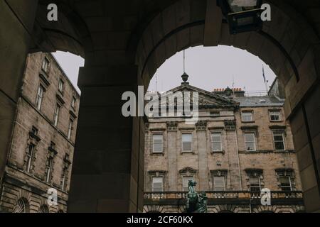 Niedriger Winkel des alten Gebäudes von Edinburgh City Chambers mit Statue im Hof von unter Bogen gesehen Stockfoto