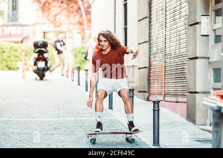 Focused Casual Mann macht Tricks beim Reiten auf Longboard an Städtische sonnige Straße Stockfoto