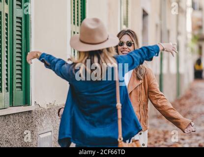 Fröhliche Frauen treffen sich und grüßen sich gegenseitig mit Umarmung Stadtstraße mit Laub Stockfoto