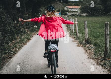 Rückansicht der Frau beim Balancieren ohne Hände auf der Landstraße am bewölkten Tag Stockfoto