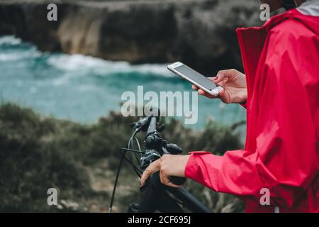 Nahaufnahme der Hand einer anonymen Frau auf dem Fahrrad, die auf dem Mobiltelefon surft Stockfoto