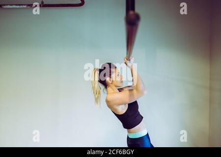 Junge Frau macht Pull-ups im Fitnessstudio Stockfoto