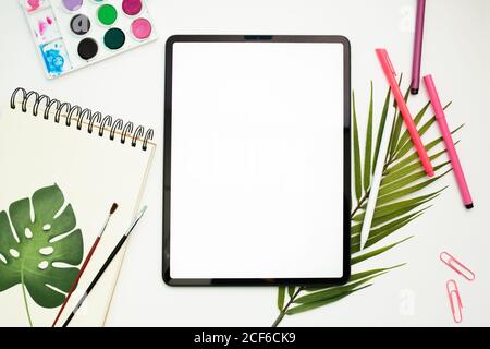 Draufsicht auf das Tablet mit leerem Bildschirm und Eingabestift Auf Tisch mit Skizzenbuch und bunten Filzstiften Stockfoto